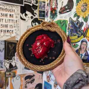 Heart sculpture in round gold frame, with blood drops