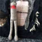 Grey and red knitted doll creature.