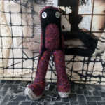 Rusty purple and black knitted doll creature.